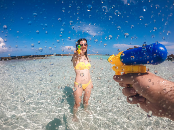 一对夫妇在海滩上玩水枪图片下载