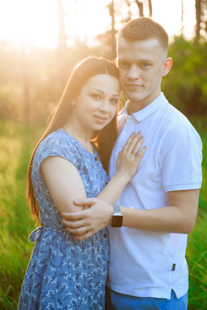 幸福的情侣在春天的夕阳下相爱。女人和男人牵手拥抱。图片下载