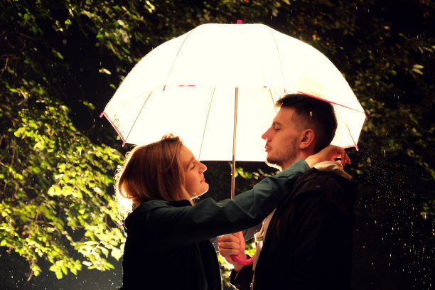雨夜，一对年轻夫妇站在伞下图片下载