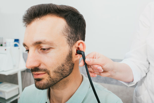 听力障碍诊断，鼓室测量，听力测试。一名男子正在进行听力诊断，他的耳朵里有一个特殊的耳机。图片下载