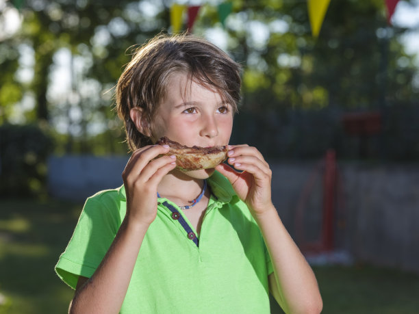 小男孩在烤架上吃猪肉图片下载