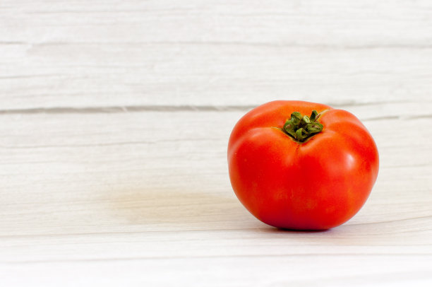 番茄放在木砧板上，灰色木桌上，番茄孤立。关闭宏。图片下载