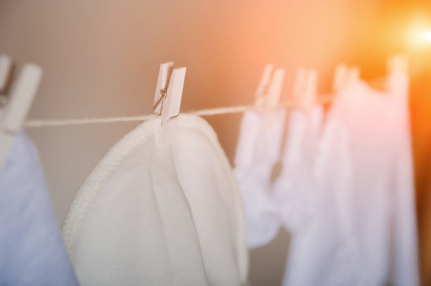 衣服的概念。清洁，熨烫，洗孩子的衣服。婴儿的东西在绳子上干特写和复制空间在灰色的墙壁背景。图片下载