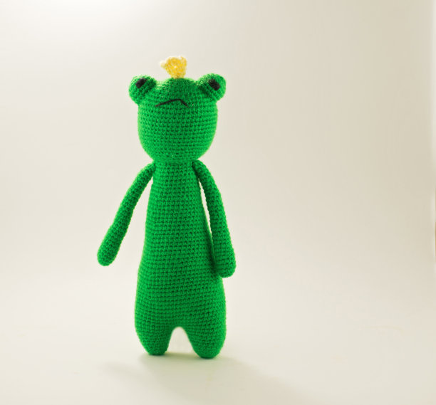 针织青蛙在白色的背景。手工玩具-绿色青蛙宝宝。图片下载