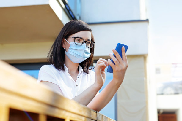 视频电话。在家工作，戴面具的女人。新的现实。图片下载