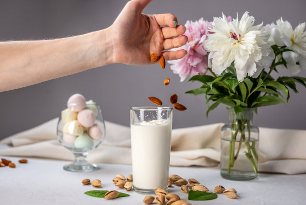 手正在把杏仁倒进一杯天然杏仁牛奶里。健康饮食的替代素食饮料图片下载