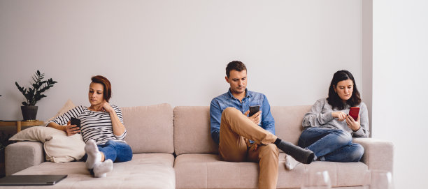 朋友坐在沙发上，用着智能手机图片下载