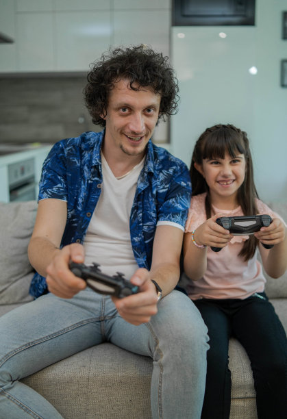 快乐的年轻父亲喜欢玩电子游戏与幼小的女儿图片下载