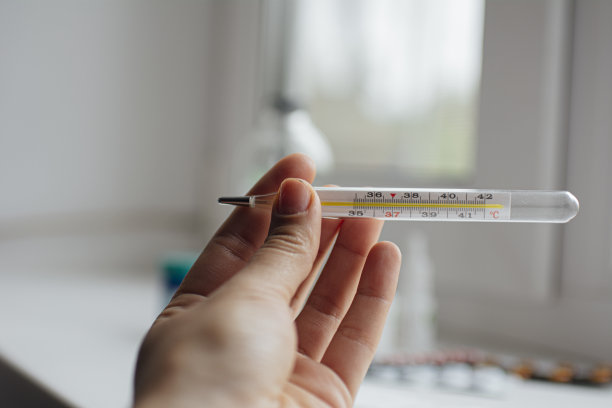 医疗温度计在手的背景上的急救箱和各种药丸图片下载