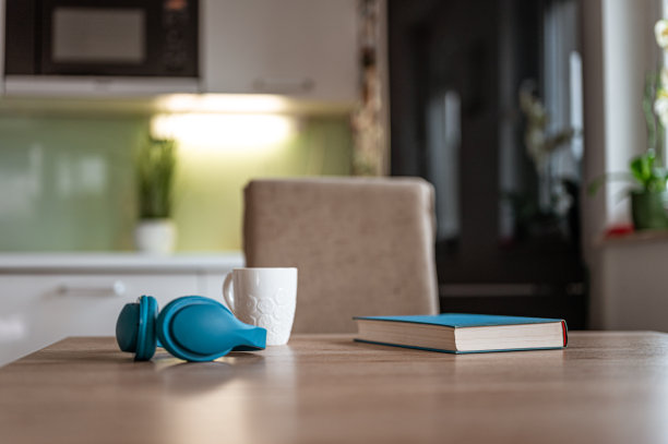 书，耳机和厨房桌子上的一个白色杯子图片下载