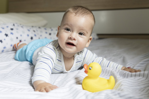 一个下雨天，小男孩和一只黄色的鸭子在床上玩图片下载