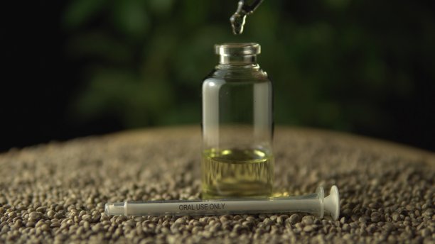医用吸液器滴注许可大麻CBD油。背景:小玻璃瓶和注射器，仅供口腔使用。在木桌上种植生物种子和大麻。图片下载