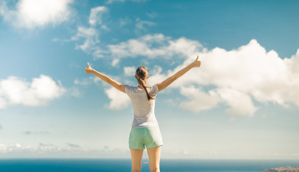 自由幸福的女人对着夕阳的天空举起双臂图片下载