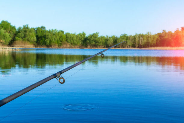 夏天在河边钓鱼。鱼竿给料机，从船上钓鱼。用于复制文本的空间。有选择性的重点图片下载