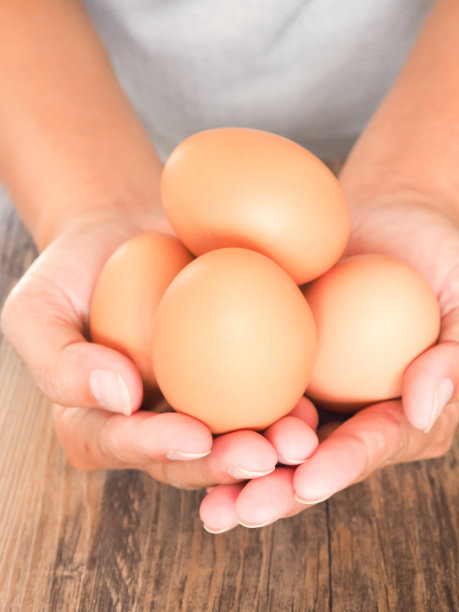 木背景上的一个女人手里拿着新鲜的鸡蛋。高蛋白和维生素的食物。图片下载