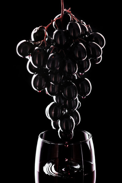 葡萄滴酒入酒杯。红酒倒入酒杯。孤立在黑色背景上。边境艺术设计图片下载