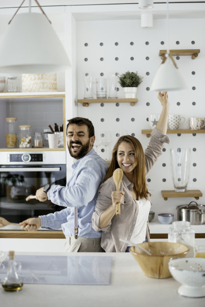 快乐的夫妇有乐趣，跳舞和唱歌在厨房在家里的上午库存照片图片下载