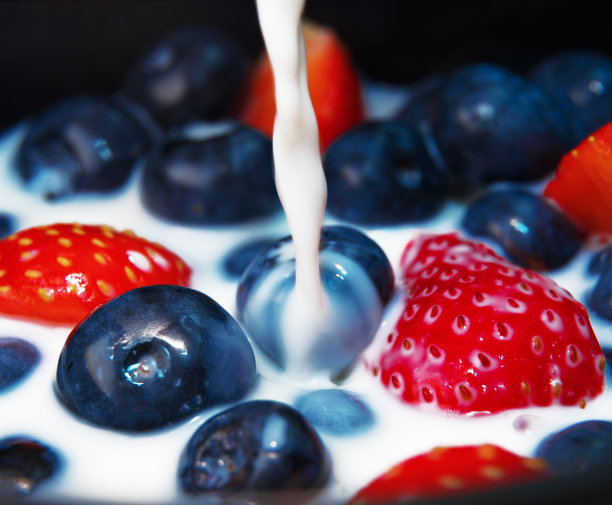 牛奶倒在蓝莓和草莓上。微距镜头。图片下载