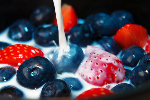 牛奶倒在蓝莓和草莓上。微距镜头。图片下载