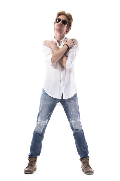 帅气的红发男模特穿着牛仔裤和白衬衫，双手搭在肩膀上摆姿势。图片下载