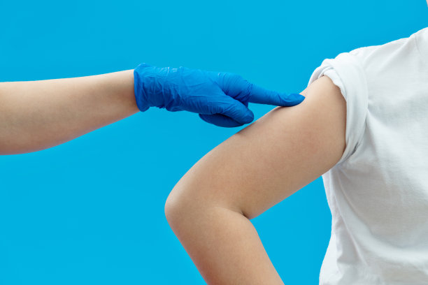 医生为蓝色背景的男孩接种疫苗图片下载