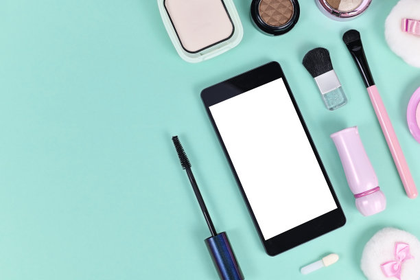平躺与空白的黑色智能手机与空白的白色屏幕包围彩妆美容产品在浅绿色的背景与拷贝空间在左侧图片下载