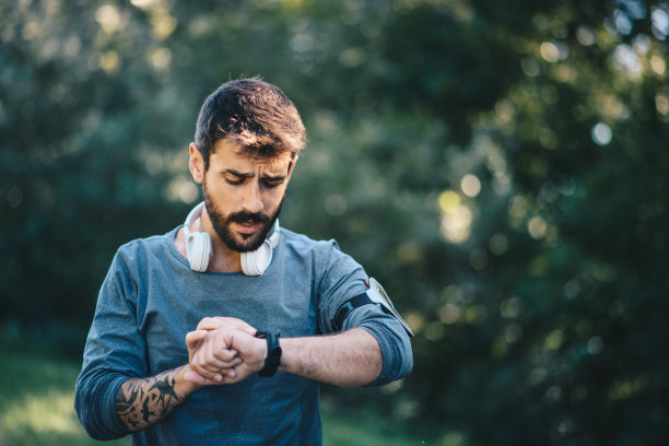 一位年轻瘦削的白人男子在训练中看着他的手表图片下载