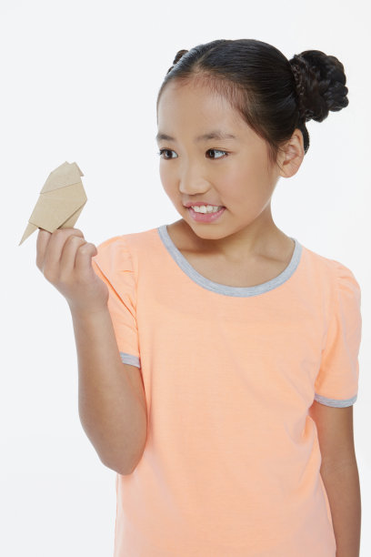 可爱的女孩举着一只纸鸟图片下载