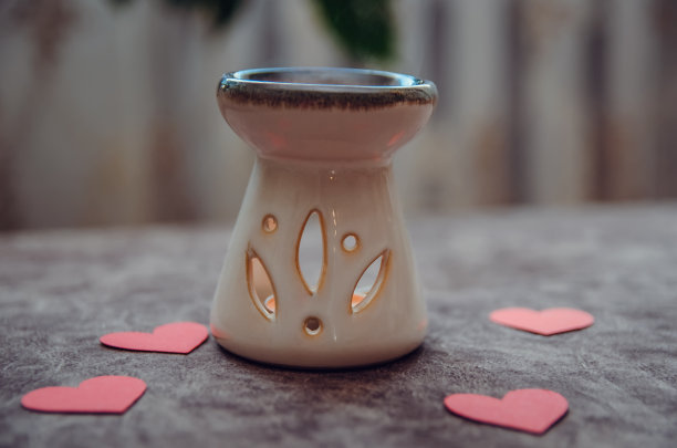 红心中间的沙发上放着一盏点着蜡烛的香薰灯。浪漫的背景图片下载