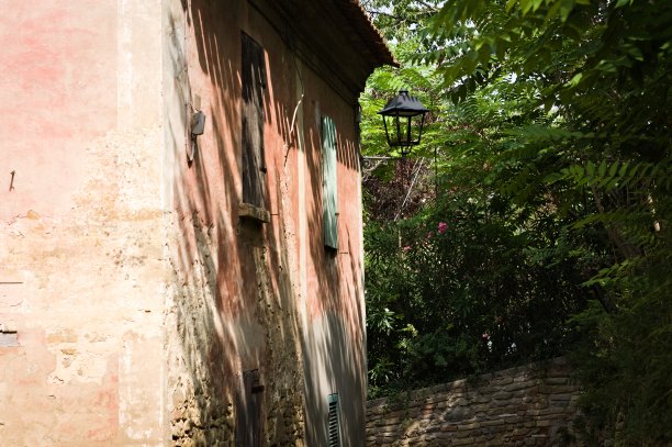 花园附近屋顶下墙上挂着路灯的老房子(Fiorenzuola di Focara, Pesaro，意大利，欧洲)图片下载