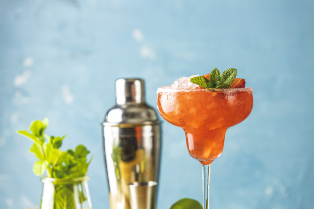 冰冻草莓酸橙薄荷玛格丽塔在高脚玻璃杯靠近与酒吧工具和配料的木桌。高档酒精鲜饮。图片下载