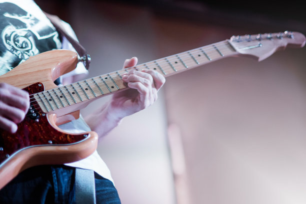 这位音乐家在舞台上弹电吉他。吉他颈部特写在音乐会的摇滚音乐在一个音乐家的手中。手指在指图片下载