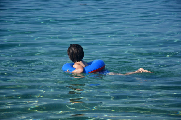 小男孩带着充气圈在海里游泳图片下载