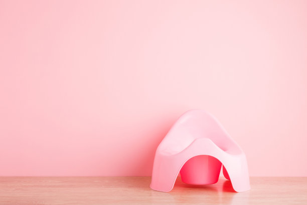 墙上地板上的婴儿便盆。前视图。特写镜头。浅粉色背景上的空白文本位置。柔和的颜色。图片下载