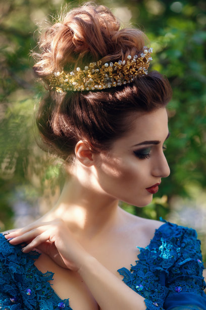 身穿绿色华丽礼服、头戴皇冠的自然美景中的女子。公园里的美丽新娘模特。户外发型女士图片下载