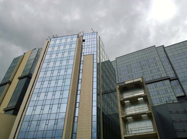 新建会展大厦、企业商务中心。玻璃表面。出租商业地产。城市景观。办公园区。阴暗的天空。经济和金融概念。城市建筑。图片下载