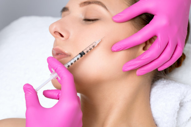 美丽的女人在美容院。美容师在脸部、眼部和颧骨注射抗皱针剂。美容院的女性美容。图片下载