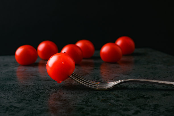 叉子上放一个番茄，背景是黑色的图片下载
