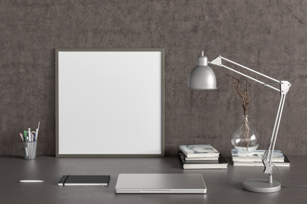 方形海报框架模型在家庭工作室工作空间的黑色桌子上，混凝土墙。正面视图，剪贴路径周围的海报图片。图片下载