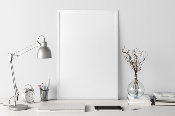 垂直的海报框架模型在家庭工作室工作空间的白色桌子上，白色的墙壁。正面视图，剪贴路径周围的海报图片。图片下载