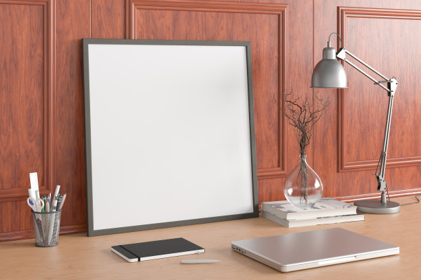 方形海报框架模型放在家庭工作室工作空间的木桌上，带有古典风格的装饰墙。侧视图，剪贴路径周围的海报图片。图片下载
