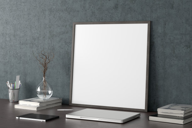 方形海报框架模型在家庭工作室工作空间的黑色桌子上，混凝土墙。侧视图，剪贴路径周围的海报图片。图片下载