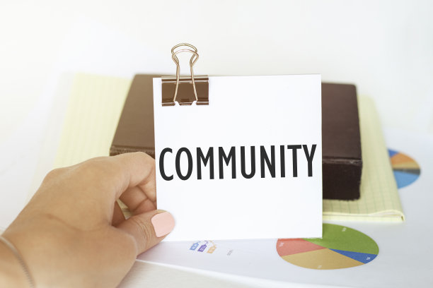 女人手里拿着一张带有文字共同体背景图和记事本的纸图片下载