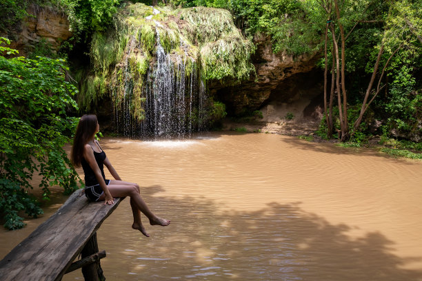 女孩和美丽的瀑布和泻湖在夏天放松。图片下载