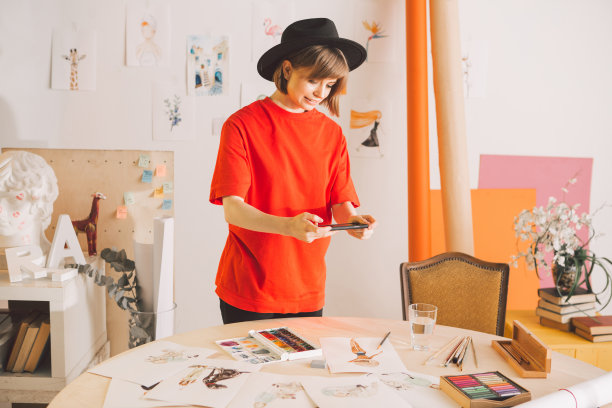 插画家女孩博主用手机拍摄水彩画。摄影为广告课程插图或博客图片下载