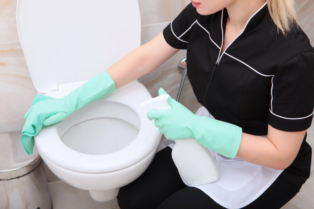 一个穿着清洁服务制服的女孩在清洁浴室里的厕所。认不出来照片。清洁和卫生的概念。图片下载