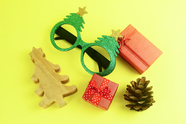 顶部布局视图红色礼盒装饰松果和绿色花哨的眼镜和小木材圣诞树。图片下载