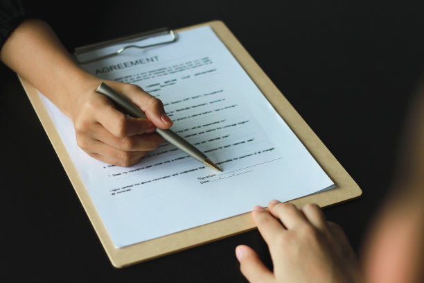 一位妇女签署了一份文件，成为办公室的新雇员。合同和工作申请的概念图片下载