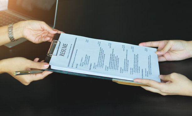 一名年轻女子向人力资源经理发送了一份简历，以考虑她的申请。人力资源经理做出雇用决定。采访的概念。图片下载