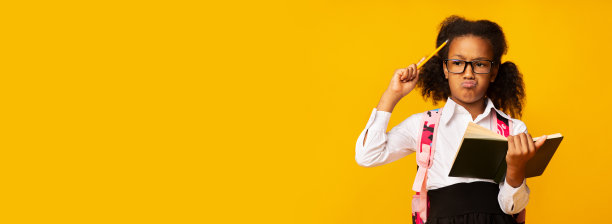 女学生拿着书在黄色背景上做作业，全景图图片下载